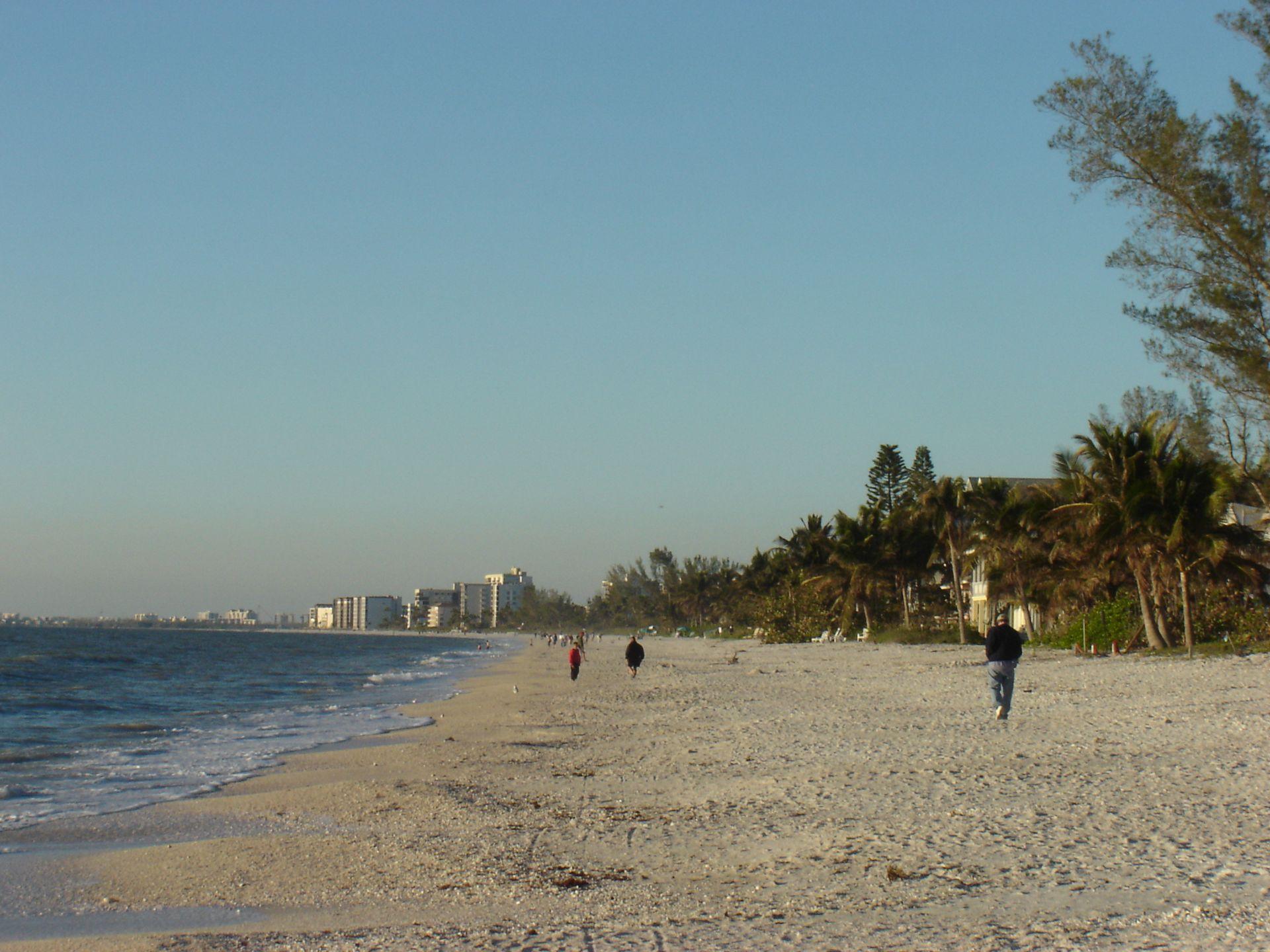 Walkers on the white-sand shoreline of Bonita Beach