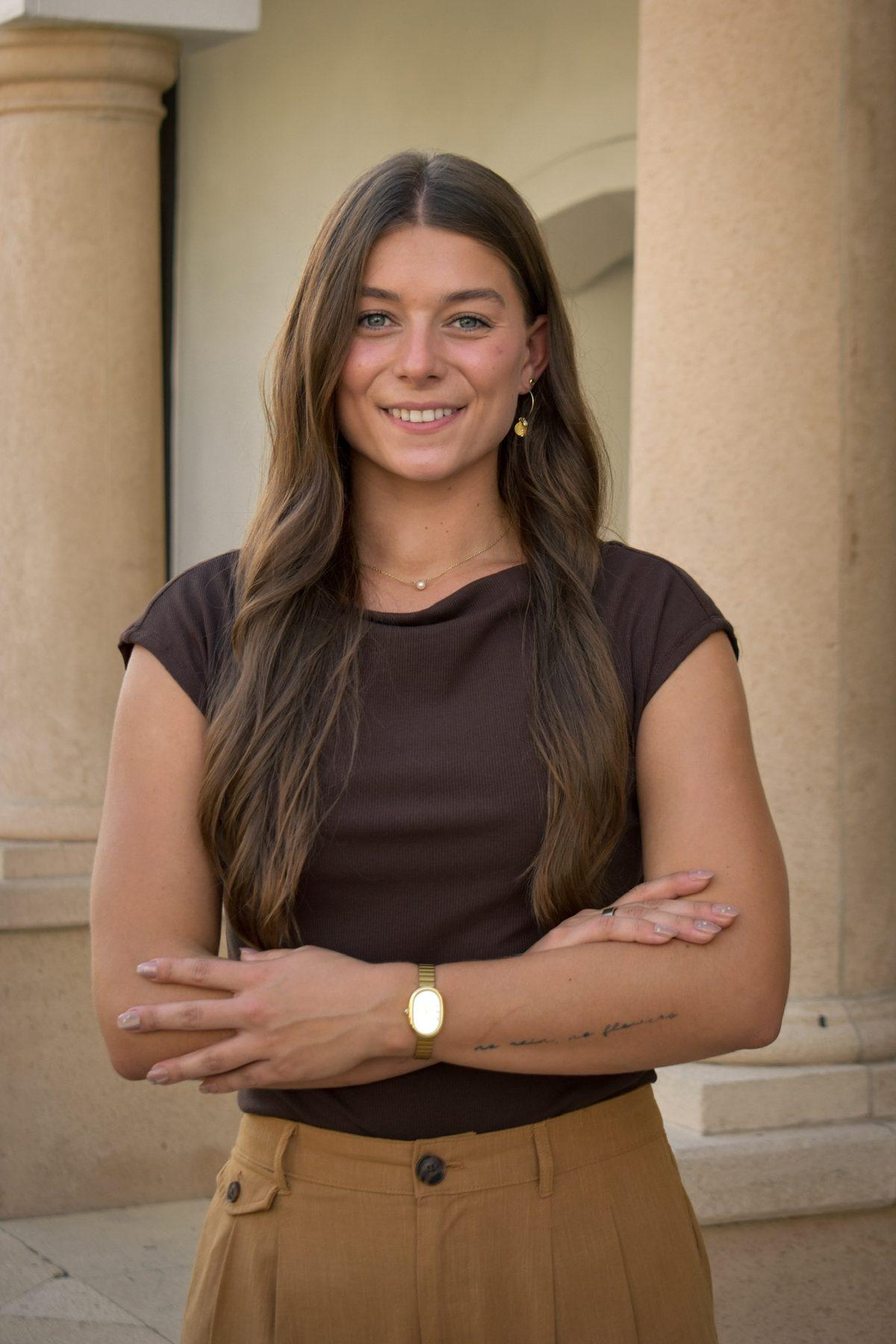 Simone Kohl, Southwest Florida REALTOR®, standing with arms crossed beside sandstone columns